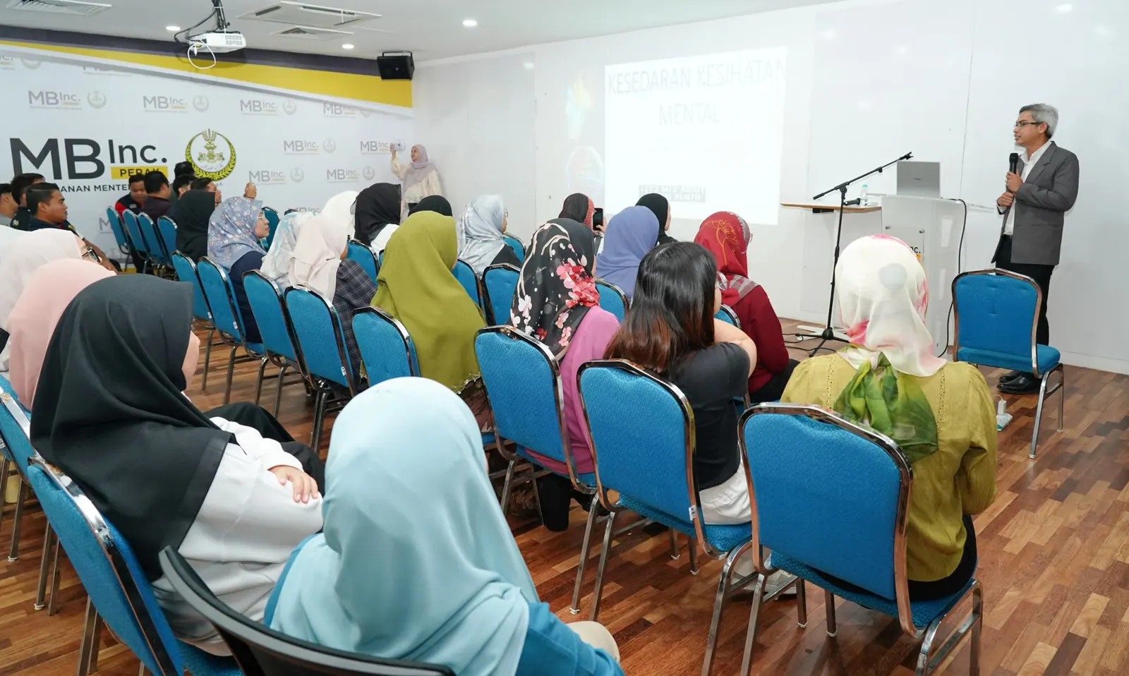Facilitator speaking to participants during a mental health awareness session at MBInc